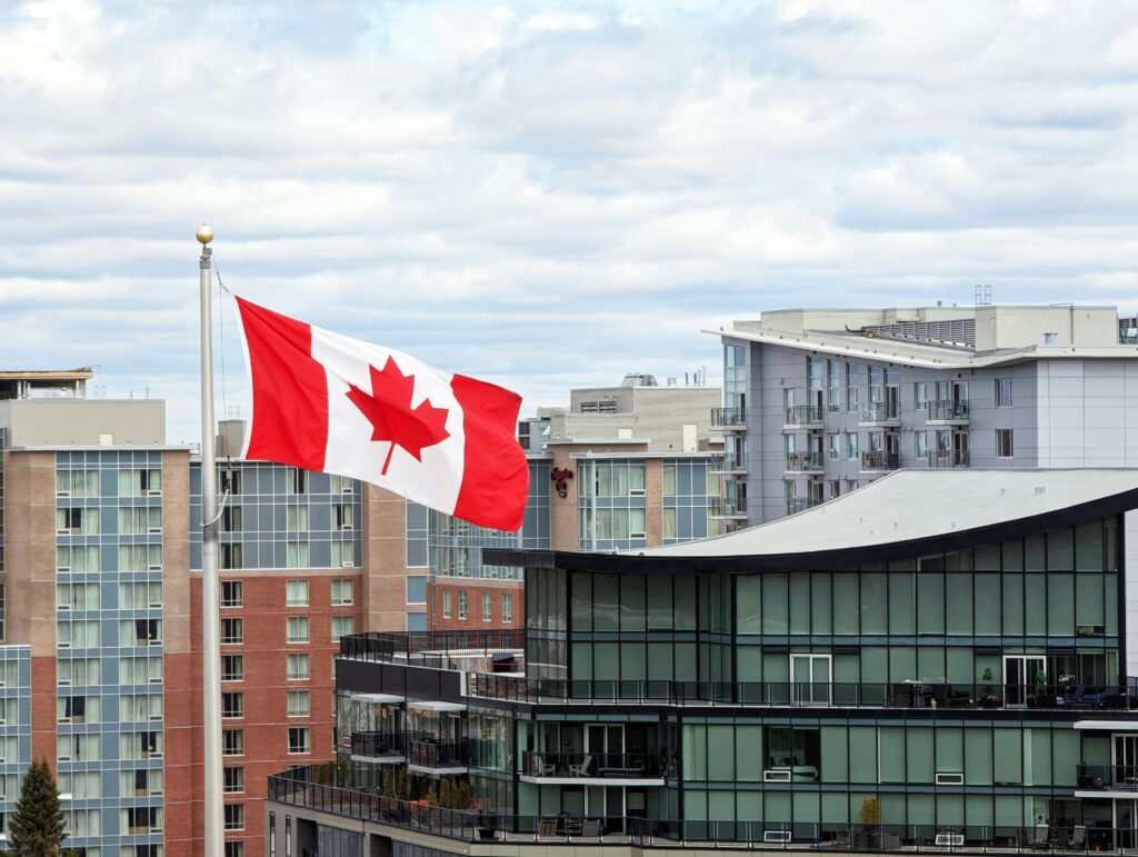 Canadian flag waving prominently in Halifax skyline with modern architecture.